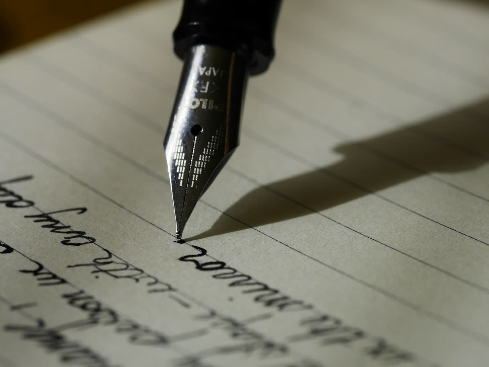 Close-up of a hand writing English sentences in a notebook